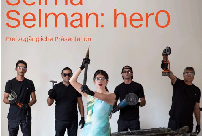 Umjetnica Selma Selman u prvom planu drži sjekiru, iza nje 4 muškarca sa alatima.